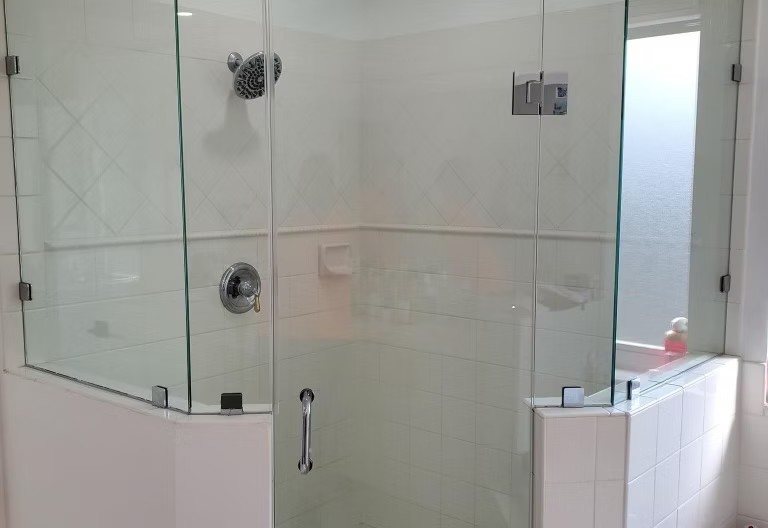 White tiled shower with chrome fixtures and multi-panel glass enclosure