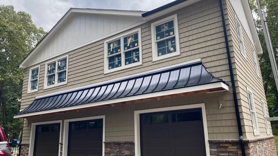 Exterior construction project with siding, windows, stonework, and roof details