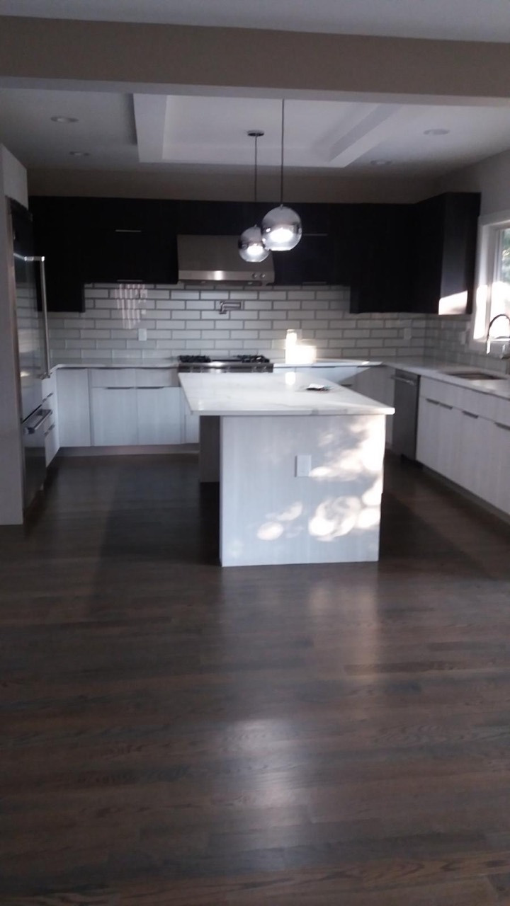 Two-tone kitchen with light lower cabinets, dark upper cabinets, subway tile, central island, and dark wood floor