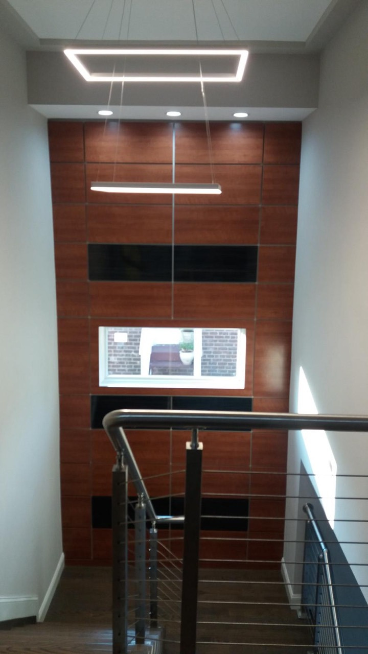Modern stair detail with dark wood, horizontal cable railings, and a paneled accent wall